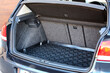 © Татьяна Богуто - Open car trunk with dark carpeted lining, textured black rubber mat, and a red fire extinguisher mounted on the right, showing organized storage space in a blue hatchback