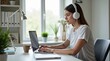 © Михаил Ибрагимов - Young woman working on laptop while wearing headphones at home