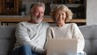 © Johannes - Happy mature mid age couple using laptop sit on sofa doing ecommerce shopping online on website. Smiling senior old adult man and woman looking at computer buying insurance browsing internet at home.