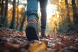 © FINS - A person enjoying a hike on a fall path through the woods, with golden leaves covering the ground and the sun setting in the background.