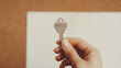 © Sana Sabina - Hand holding a key over a blank notebook on a wooden background