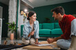 © Miljan Živković - Couple assembling furniture reading instructions in living room