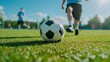 © Zaur - A group of young men playing soccer on a sunny day. One player in the foreground kicking a black and white ball.