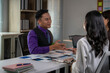 © Wasana - A man in a purple shirt and vest is talking to two women at a desk