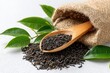 © sendok - Loose black tea in wooden spoon, burlap bag, and leaves