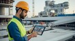 © JHO_DSN - Construction engineer reviewing building plans on a tablet at construction site