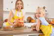 © Pixel-Shot - Cute little girl and her mother with carved Halloween pumpkin in kitchen