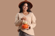 © Pixel-Shot - Beautiful young happy African-American woman with pumpkins on beige background