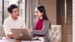 © Pichsakul - Asian business professionals discussing project on laptop modern office adult male female collaboration customer service communication strategy