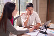 © Pichsakul - Asian business professionals face work stress colleague provides support during challenging financial report review office meeting