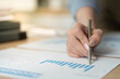 © wichayada - Data Analysis. Woman reviewing financial graphs and charts with a pen.