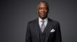 © PTC - Confident mature Black businessman in a formal suit posing for a corporate headshot. Portrait of an experienced professional leader.