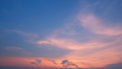 Wall Mural - A timelapse video captures a peaceful sunset sky where soft pink and orange clouds gently float across a calm blue backdrop, illustrating the smooth transition from day to dusk in a serene atmosphere.