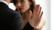 © Ketanoff - In a calm indoor environment, a woman raises her hand to signal stop as she addresses harassment, visibly expressing defiance and courage against inappropriate behavior