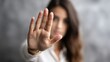 © Ketanoff - In a calm indoor environment, a woman raises her hand to signal stop as she addresses harassment, visibly expressing defiance and courage against inappropriate behavior