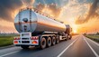 © Kinza - A silver tanker truck driving on a highway at sunset with a cloudy sky in the background