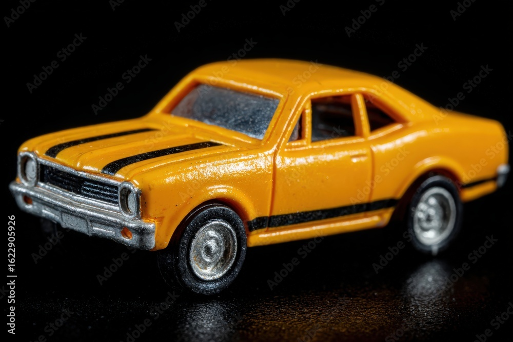 A vibrant yellow toy car with black stripes is positioned on a glossy black surface. The model exhibits fine details, highlighting its classic design and appealing color.