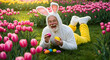 © Nur - Happy Easter! A joyful senior man in a bunny costume enjoys a spring day amongst colorful tulips, playfully holding Easter eggs.