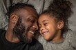 © Serhii - Joyful Bonding: Black Father and Daughter Smiling Together in Cozy Home Environment