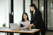 © Thitisak - Two Asian businesswomen working together in an office.