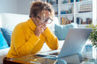 © simona - Middle-aged woman using laptop at home in living room, wearing yellow oversized sweater, smiling and relaxed, enjoying leisure time, casual digital activity, browsing, chatting or entertainment