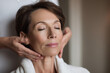 © EricMiguel - Relaxed middle-aged woman enjoying a soothing facial massage in a calm spa environment
