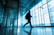 © jay - Professional businessperson walking in modern office lobby with glass walls reflecting sunlight, symbolizing corporate environment and productivity