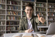 © fizkes - Study success in blended learning. Portrait smiling male zoomer high school student sitting at classroom desk use notebook open books show thumbs up to camera completing task enjoying productive work