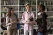 © fizkes - Cool and stylish young scholars. Three diverse teen friends modern high school university students peers meet in library for self study engaged in casual conversation hold books share news with smiles