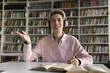 © fizkes - Confident remote speaker. Webcam portrait smart smiling teen male student in wireless headset sit at desk with study materials speak at online education event answer teacher question at virtual class