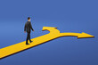 © Who is Danny - Businessman walking on yellow path that forks into two arrows symbolizing career decision, strategy, or life choice on blue background.