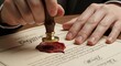 © vactorfol1 - Photo of closeup of a hand pressing a traditional wax seal onto an official document, symbolizing authority and certification