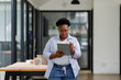 © David - African American business woman using digital tablet while standing in workplace office. Black confident woman working on digital tablet in meeting room with copy space. Happy successful woman.