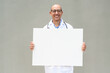 © Ranta Images - Hispanic Male Doctor in Lab Coat with Stethoscope on Plain Background Holding Empty Placard