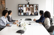 © fizkes - International business collaboration. Multiethnic businesspeople corporate employees gather at boardroom for hybrid virtual conference with colleagues join group meeting via videocall on large screen