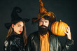 © Volodymyr - Party for happy Halloween couple. Halloween couple with pumpkin and Halloween makeup. Man and woman in witch hat celebrating Halloween.
