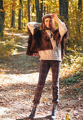Wall Mural - Autumn girl in good mood posing outdoor. Dreamy girl. Beauty model, young beautiful woman hold autumn leaves. Romantic woman in autumn park. Autumn fall concept.
