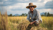 © Jhati - A farmer harvesting rice in a field wearing a hat and striped shirt outdoors