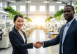 © Kavintha - Businesswoman and businessman from diverse backgrounds shaking hands in an office.