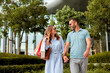 © BGStock72 - Couple enjoys a sunny day while shopping together in an urban outdoor plaza surrounded by beautiful greenery