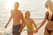 © BGStock72 - Family enjoying a joyful walk along the beach during sunset moments