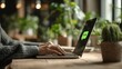 © AbirHasanSelim - Person working on a laptop in a cozy cafe surrounded by lush green plants and warm lighting