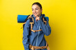© luismolinero - Young mountaineer woman with a big backpack over isolated yellow background looking to the side and smiling