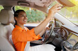 © Anastasiya - African American woman adjusting rearview mirror before driving car. Young black female focused and smiling, showing readiness and responsibility, closeup