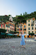 © Olga - Stylish blonde tourist exploring charming European coastal town at sunset.