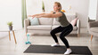 © Prostock-studio - Home training concept. Active mature lady doing squats on yoga mat indoors, copy space. Sporty senior woman exercising her legs, having domestic workout during covid isolation