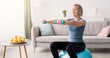 © Prostock-studio - Strong mature woman working out with dumbbells on fitness ball at home, blank space. Fit senior lady taking care of her health, having domestic training, leading active lifesyle, indoors