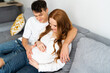 © ADDICTIVE STOCK - Young couple expecting a baby sitting together on couch