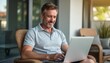 © natakot - Smiling man working on a laptop in a cozy outdoor setting