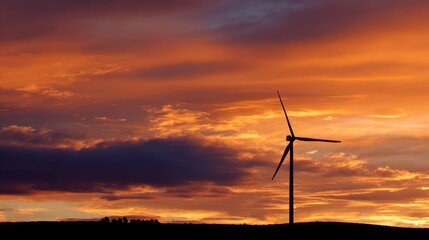Wall Mural - A striking display of colors fills the sky at sunset, casting dramatic hues of orange and purple. A tall wind turbine stands in silhouette, surrounded by serene countryside.